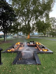 a fire pit in the middle of a grassy area with couches and candles on it