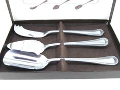 four silver spoons in a box on a table