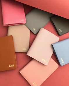 five different colored leather wallets sitting next to each other on a pink surface,