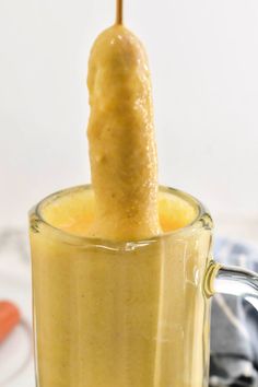 a banana sticking out of the top of a cup filled with orange juice and liquid