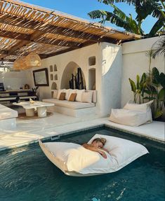 a woman laying on top of a bean bag chair next to a swimming pool with lounge chairs