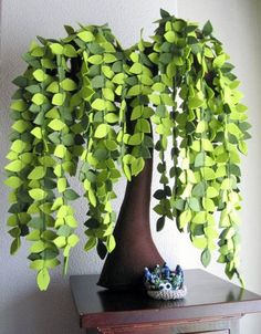 a potted plant with green leaves on top of a wooden table next to a white wall