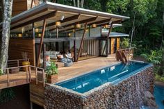 a house with a swimming pool in the middle of it and trees surrounding it, surrounded by greenery