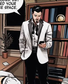 a man in a suit and tie looking at his cell phone while standing next to a bookcase