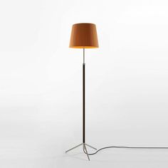 a floor lamp with a brown shade on the base and a light bulb plugged in