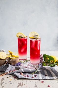 two glasses filled with pink lemonade on top of a table next to sliced lemons