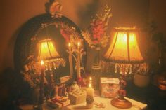 two lamps are sitting on a table in front of a mirror with candles and gifts