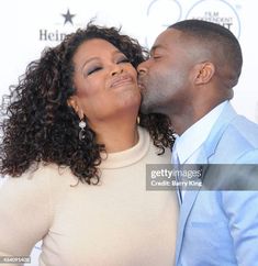 a man and woman kissing each other on the red carpet at an award ceremony in los