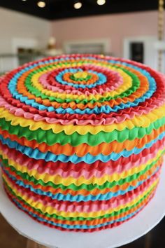 a multicolored cake is sitting on a table