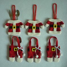 six red and white santa clause christmas ornaments with silverware in their hands, one is holding a fork