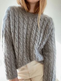 a woman wearing a gray sweater and tan pants