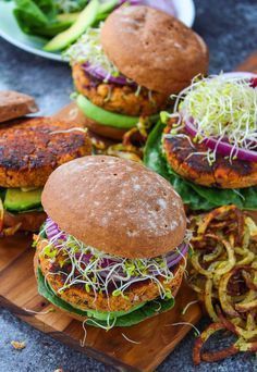 several burgers with lettuce and other vegetables on a cutting board