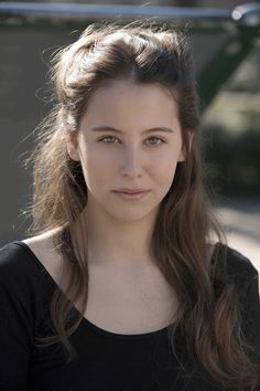 a woman with long hair and black shirt looking at the camera