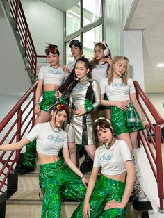 a group of young women in green and white outfits posing for a photo on some stairs