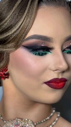 a woman with red lipstick and green eyeshade wearing a necklace, earrings and jewelry