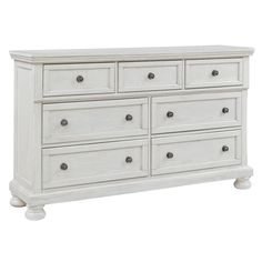 a white dresser with drawers and knobs on the bottom drawer, against a white background