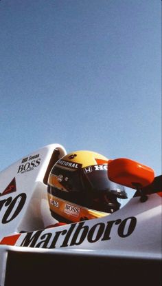 a man riding on the back of a white race car in front of a blue sky