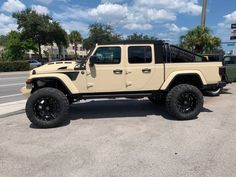 a beige jeep parked in a parking lot next to a palm tree and street sign