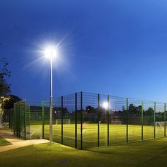 an empty baseball field at night with the lights on and grass in the foreground