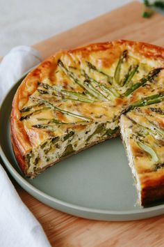 a cheese and asparagus quiche on a plate with one slice cut out