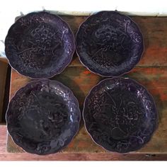 four purple plates sitting on top of a wooden table