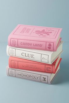 three books stacked on top of each other with the title clue written in pink and white