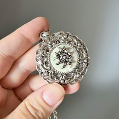 Beautiful filigree Edelweiss pendant necklace is a favorite motif in Bavarian women's jewelry for a dirndl (Bavarian traditional dress) or costume. The metal edelweiss flower is placed on a round mother-of-pearl plate and framed into a round frame with a delicate filigree pattern.  A pendant on a long chain, which you can also replace with a leather or fabric cord and wear the jewelry in different variations. ⚜️Dimensions:  Pendant: 4.5 cm // 1.7" Chain : 60 cm // 24" ⚜️ Vintage condition with t Traditional Filigree Flower Pendant Jewelry, Silver Filigree Flower Pendant Jewelry, Vintage Filigree Flower Pendant Jewelry, Silver Filigree Flower Pendant Necklace, Bavarian Wedding, Bavarian Costume, Edelweiss Flower, Filigree Pattern, Filigree Necklaces