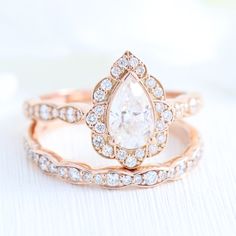 two rose gold wedding rings set with a pear shaped diamond in the center and an intricate band