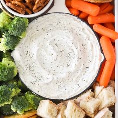 a platter with carrots, broccoli, bread and dip in it