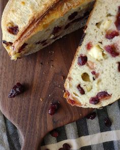 a loaf of bread sitting on top of a wooden cutting board next to raisins