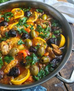 a pan filled with meat and vegetables on top of a wooden table