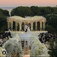 a bride and groom standing in front of an outdoor ceremony set up with white flowers