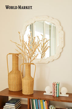 two vases and a mirror are sitting on a shelf in front of a bookshelf