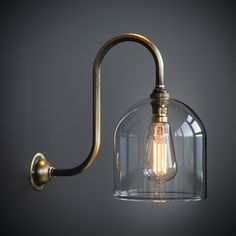 a light that is on the wall with a glass dome and a metal hook attached to it