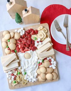 a wooden plate topped with lots of food next to a knife and fork on top of a table