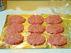 some hamburger patties are sitting on a piece of tin foil and ready to be cooked