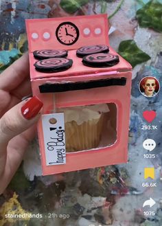 a pink toy oven with cupcakes in it and a clock on the top