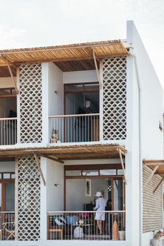 two people are standing on the balcony of a white building with wooden balconies