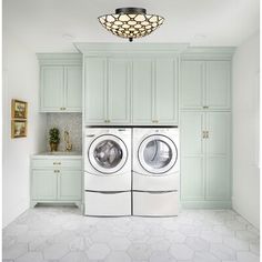 a washer and dryer in a room with light green cabinets on the walls