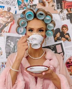 a woman with curly hair drinking from a tea cup and saucer in front of her face