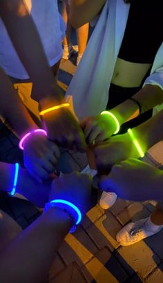 several people are holding their hands together with neon bracelets