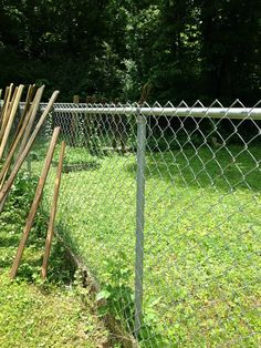 a fence that is next to a field with grass and trees in the back ground