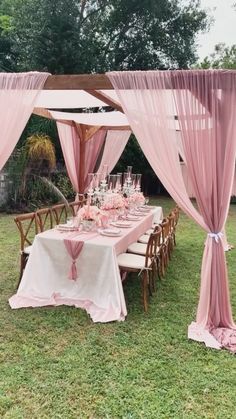 an outdoor dining area with pink drapes and table cloths set up for a party