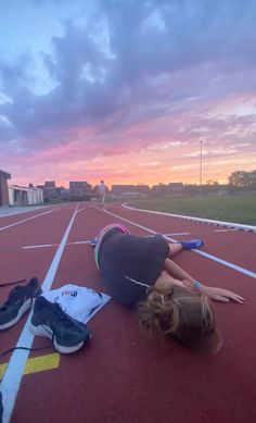 a woman is laying on the ground with her head in her hands and other sports equipment around her