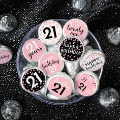 pink and black 21st birthday buttons in a glass bowl with silver foil balls around them