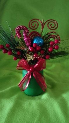 a green vase filled with red and blue ornaments on top of a green table cloth