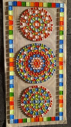 an art piece made out of different colored beads on a canvas bag with two circles in the middle