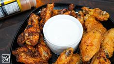 chicken wings with dipping sauce on a black plate