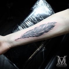 a black and white feather tattoo on the arm