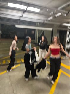 several young women are dancing in a parking garage